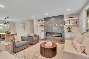 Living room featuring healthy amount of natural light, light wood-style floors, a fireplace, and recessed lighting