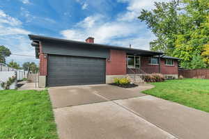 Ranch-style home with brick siding, a chimney, concrete driveway, and a garage