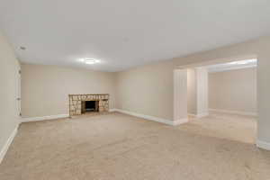 Finished below grade area featuring a stone fireplace and light colored carpet