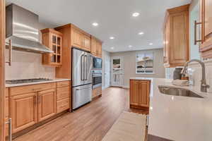 Kitchen featuring tasteful backsplash, wall chimney exhaust hood, stainless steel appliances, light wood finished floors, and recessed lighting