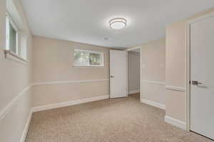 Unfurnished bedroom with light colored carpet and baseboards