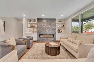Living room with light wood-type flooring, a fireplace, and recessed lighting
