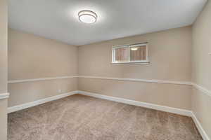 Spare room featuring light colored carpet and baseboards