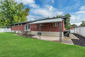 Back of house with a fenced backyard, brick siding, and a patio area