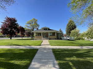 Bungalow-style house with a porch, a front lawn, brick siding, and a chimney