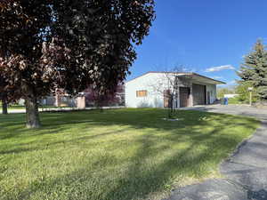 View of front of property with a front yard, a detached garage, and an outbuilding