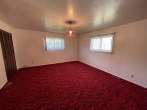 Spare room featuring a textured ceiling and dark colored carpet