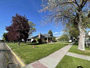 View of front facade featuring a chimney, a front lawn, and roof mounted solar panels