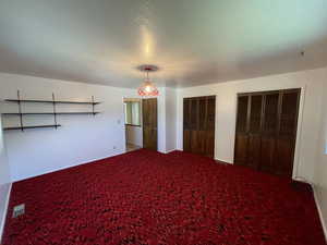 Unfurnished bedroom with two closets, carpet floors, and a textured ceiling