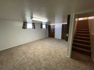 Basement with a textured ceiling, carpet floors, and stairs