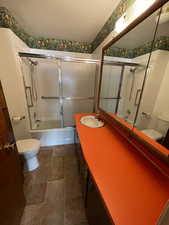 Bathroom featuring bath / shower combo with glass door, vanity, and a textured ceiling