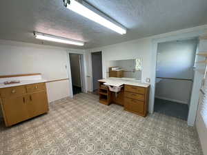 Kitchen with brown cabinets, light countertops, a textured ceiling, open shelves, and a peninsula