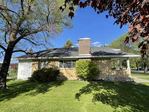 View of front of home with brick siding, a front lawn, and a chimney
