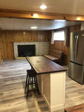 Kitchen featuring wooden walls, freestanding refrigerator, light wood-style floors, butcher block countertops, and a breakfast bar