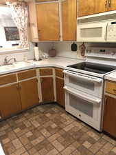 Kitchen featuring white appliances, light countertops, brick patterned floors, and brown cabinetry