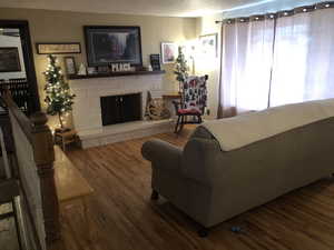 Living room with a stone fireplace and wood finished floors