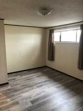 Unfurnished room featuring wood finished floors and a textured ceiling