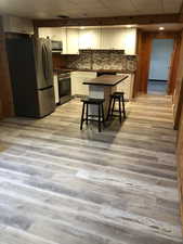 Kitchen featuring dark countertops, appliances with stainless steel finishes, white cabinetry, decorative backsplash, and a drop ceiling