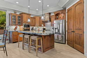 Kitchen with brown cabinets, hanging light fixtures, tasteful backsplash, appliances with stainless steel finishes, and recessed lighting