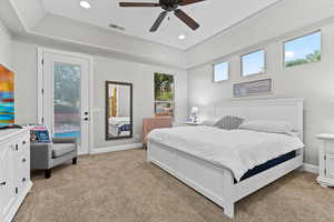 Bedroom with light colored carpet, recessed lighting, access to exterior, a tray ceiling, and ceiling fan