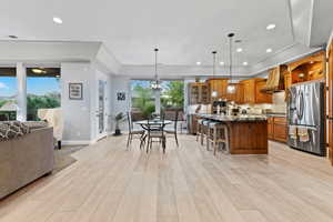 Kitchen featuring brown cabinets, decorative backsplash, dark stone counters, open floor plan, and pendant lighting
