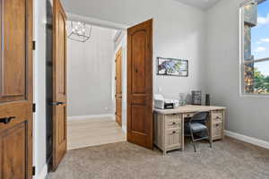 Office area with plenty of natural light, light colored carpet, and a chandelier