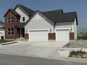 View of front facade with driveway, board and batten siding, a garage, and a shingled roof