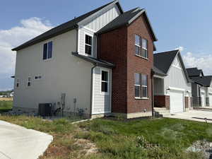 View of side of property featuring board and batten siding, driveway, brick siding, and roof with shingles