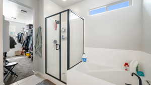 Master Bathroom with healthy amount of natural light, a garden tub, a shower stall, a walk in closet, and a textured ceiling