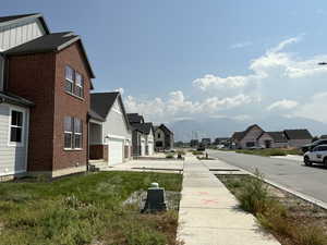 View of yard with a residential view, concrete driveway, a garage, and a mountain view