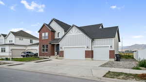 Modern farmhouse style home with board and batten siding, driveway, brick siding, a mountain view, and roof with shingles