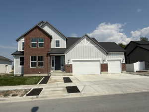 Craftsman-style house with board and batten siding, concrete driveway, a garage, and brick siding