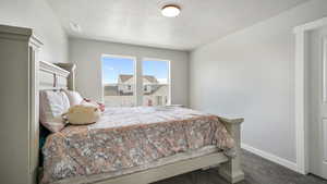 Carpeted bedroom featuring a textured ceiling and baseboards
