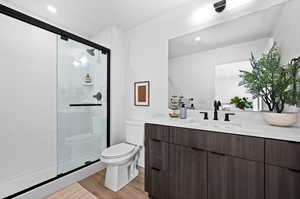 Full bath featuring vanity, a stall shower, connected bathroom, recessed lighting, and light wood-style floors