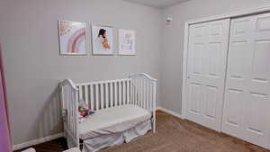 Carpeted bedroom featuring a crib and a closet