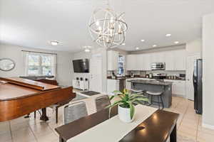 Dining area with light tile patterned floors, a chandelier, and recessed lighting