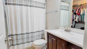 Full bathroom with a spacious closet, vanity, and a shower with shower curtain