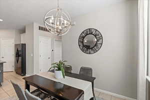 Dining space with light tile patterned floors and a chandelier