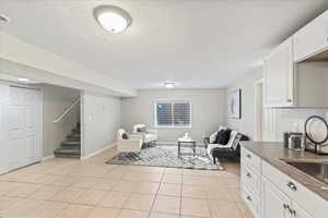 Sitting room with stairs, light tile patterned floors, and a textured ceiling