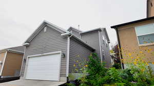 View of property exterior with concrete driveway and an attached garage
