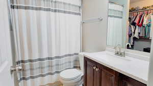 Full bathroom with a walk in closet, vanity, and a shower with shower curtain