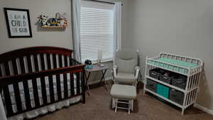 Bedroom featuring a crib and dark carpet