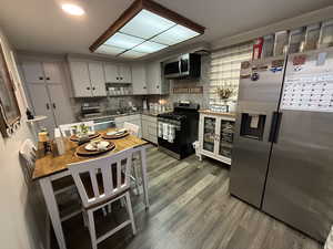 Kitchen featuring stainless steel appliances, white cabinetry, tasteful backsplash, and dark wood-type flooring