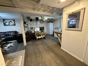 Finished basement with freestanding refrigerator and carpet