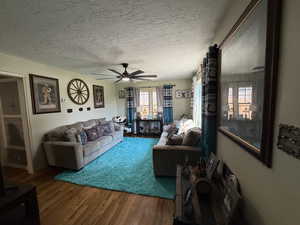 Living area featuring wood finished floors, a textured ceiling, and a ceiling fan