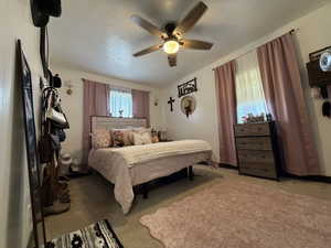 Bedroom with carpet floors, ceiling fan, and a textured ceiling