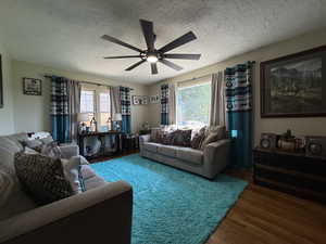Living area with wood finished floors, a textured ceiling, and a ceiling fan