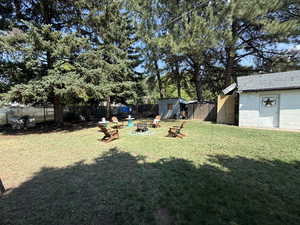 Fenced backyard with a fire pit, a storage unit, a patio, and view of scattered trees