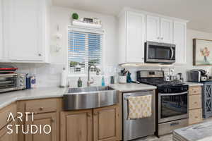 Kitchen featuring stainless steel appliances, tasteful backsplash, and white cabinets