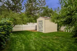 Fenced backyard featuring a shed